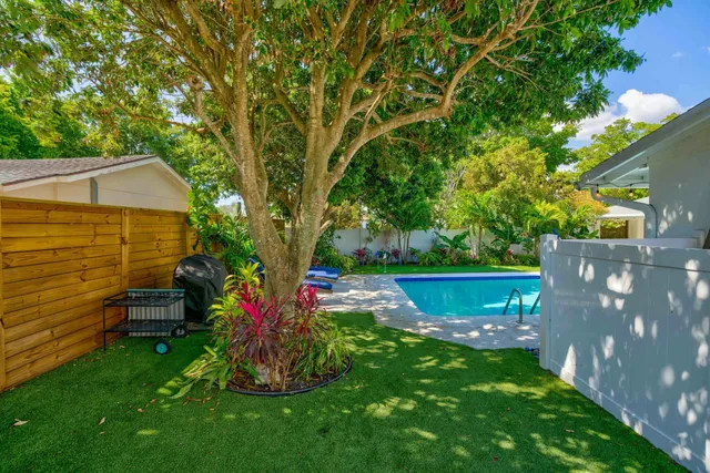 a view of a backyard with table and chairs potted plants and a large tree