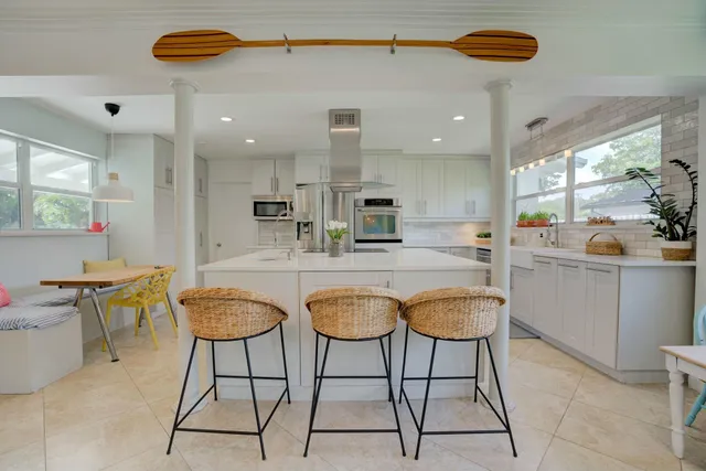 a kitchen with granite countertop a table chairs stove and white cabinets