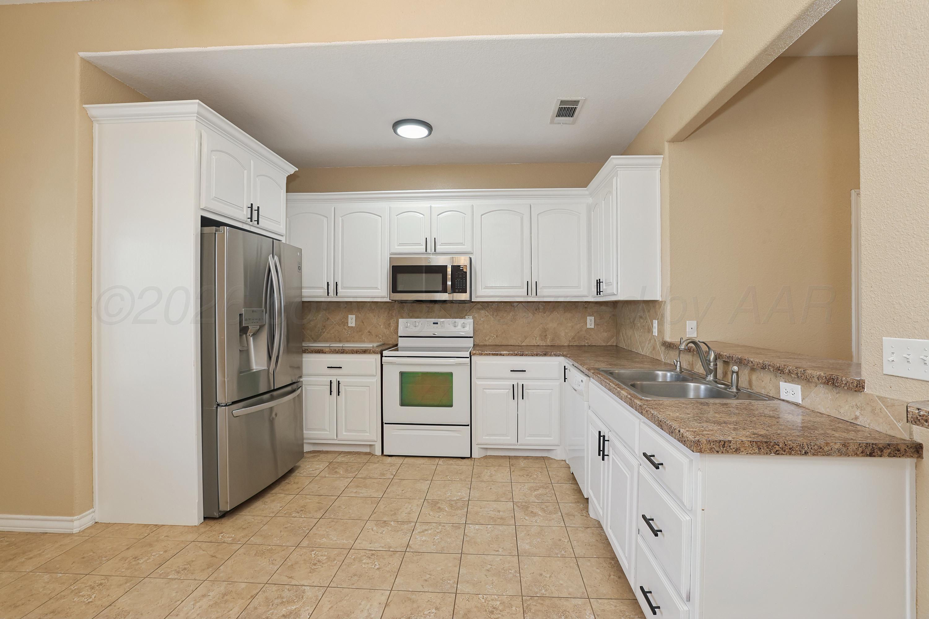 19101 Sundancer Lane Bushland, TX 79124 - Photo 5 of 25 a kitchen with granite countertop white cabinets a refrigerator and a sink