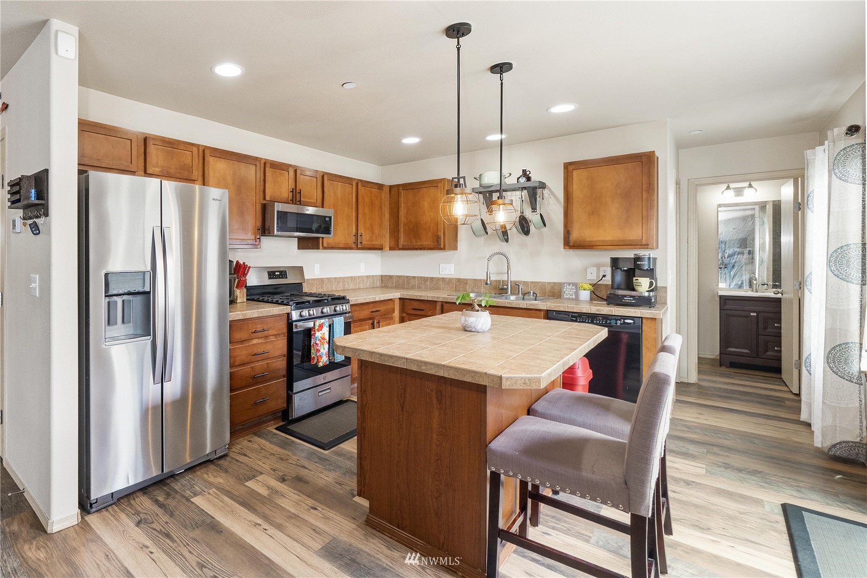 1589 Grant Avenue DuPont, WA 98327 - Photo 7 of 30 a kitchen with stainless steel appliances granite countertop a refrigerator a sink dishwasher a stove and a dining table with wooden floor