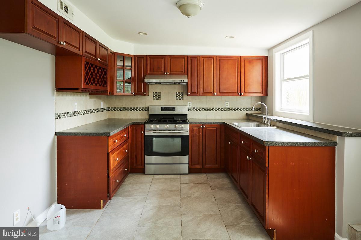 a kitchen with stainless steel appliances granite countertop wooden cabinets a sink and a stove