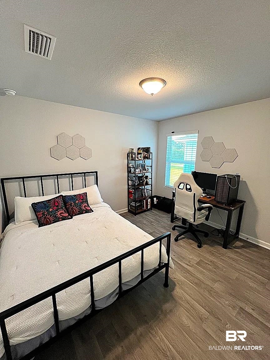 23915 Veranda Circle Elberta, AL 36530 - Photo 3 of 16 Bedroom with dark wood-style floors, a textured ceiling, and a desk