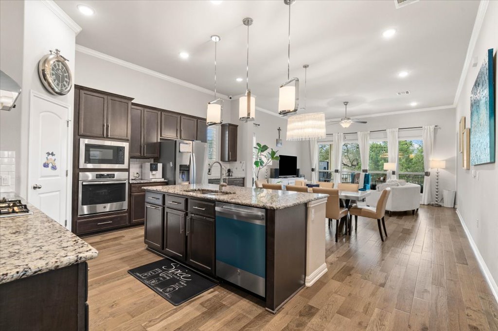 11901 Deering Place Austin, TX 78726 - Photo 6 of 40 a kitchen with stainless steel appliances granite countertop a stove top oven a refrigerator a sink and a dining table with wooden floor