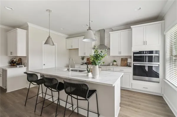 a kitchen with stainless steel appliances kitchen island granite countertop a table chairs stove and white cabinets