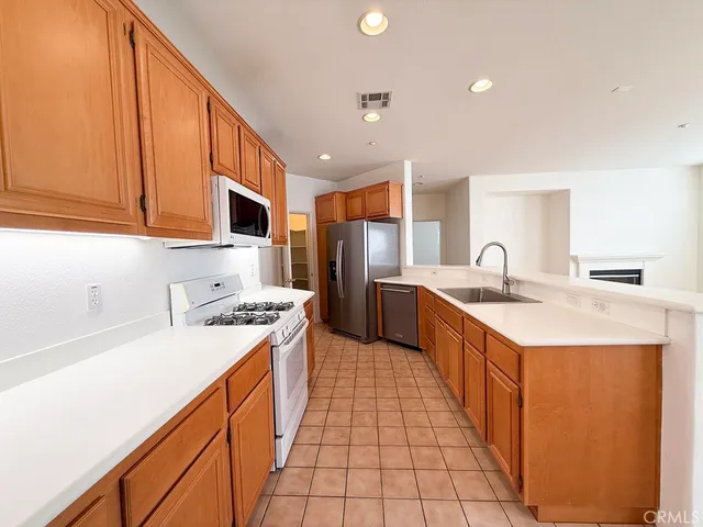 a kitchen with stainless steel appliances kitchen island granite countertop a sink a stove top oven a refrigerator and cabinets