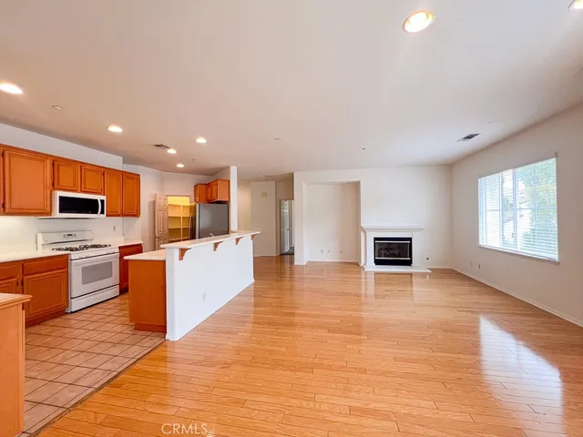 a view of kitchen with stainless steel appliances kitchen island granite countertop a stove top oven a sink dishwasher a dining table and chairs with wooden floor