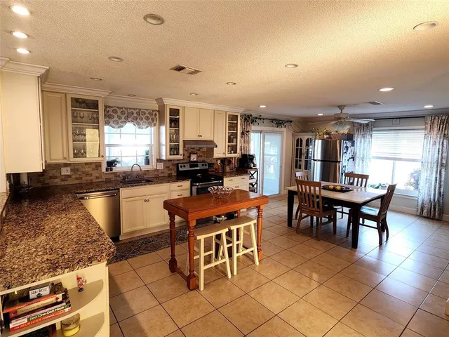 a kitchen with stainless steel appliances granite countertop a stove a sink a dining table and chairs