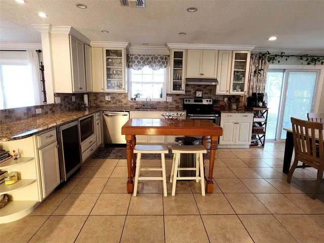 a kitchen with stainless steel appliances granite countertop a stove top oven a sink dishwasher a dining table and chairs