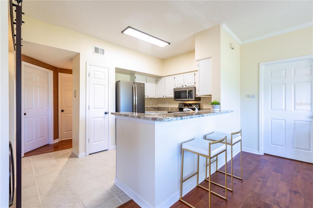 10000 Southwest 52nd Avenue, Unit 124 Gainesville, FL 32608 - Photo 11 of 33 a kitchen with stainless steel appliances kitchen island granite countertop a refrigerator and microwave