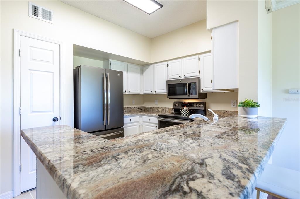 10000 Southwest 52nd Avenue, Unit 124 Gainesville, FL 32608 - Photo 9 of 33 a kitchen with granite countertop a refrigerator and a sink