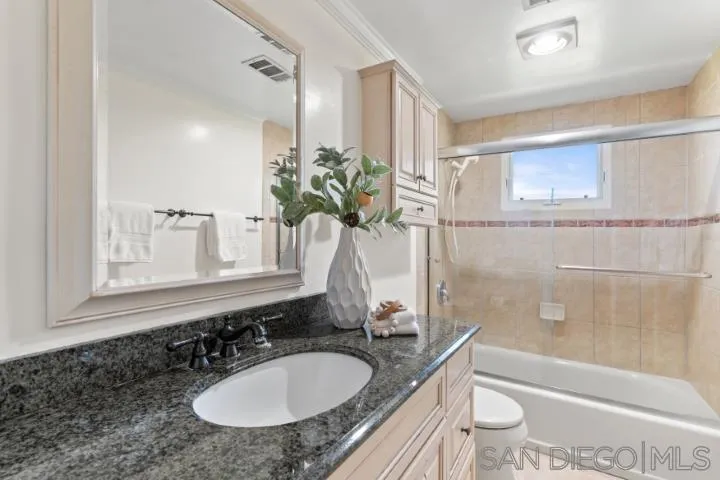 13311 Fallen Leaf Road Poway, CA 92064 - Photo 17 of 30 a bathroom with a granite countertop sink a toilet a mirror and bathtub