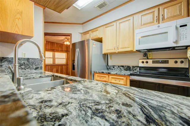 a large kitchen with stainless steel appliances granite countertop a stove a sink and a microwave