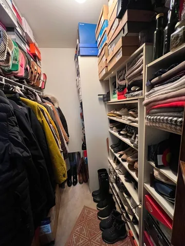 a view of walk in closet with clothes and shoes