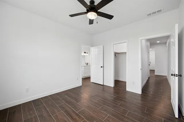 an empty room with wooden floor and a ceiling fan