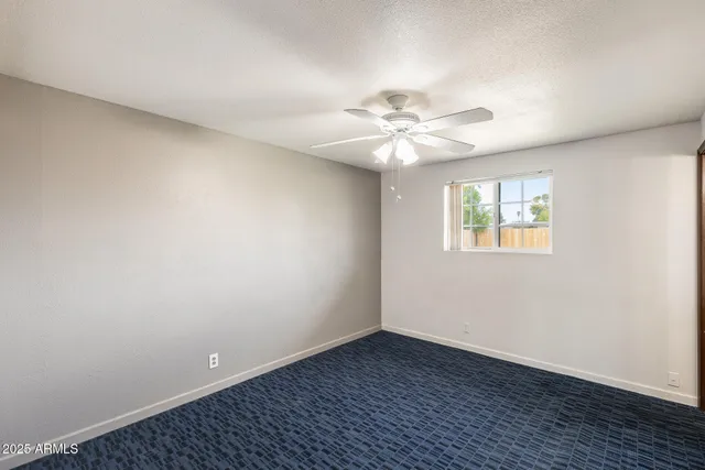 an empty room with a chandelier fan and windows