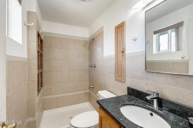 a bathroom with a granite countertop sink toilet a mirror and bathtub