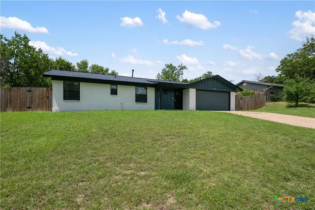 a front view of house with yard and trees in the background