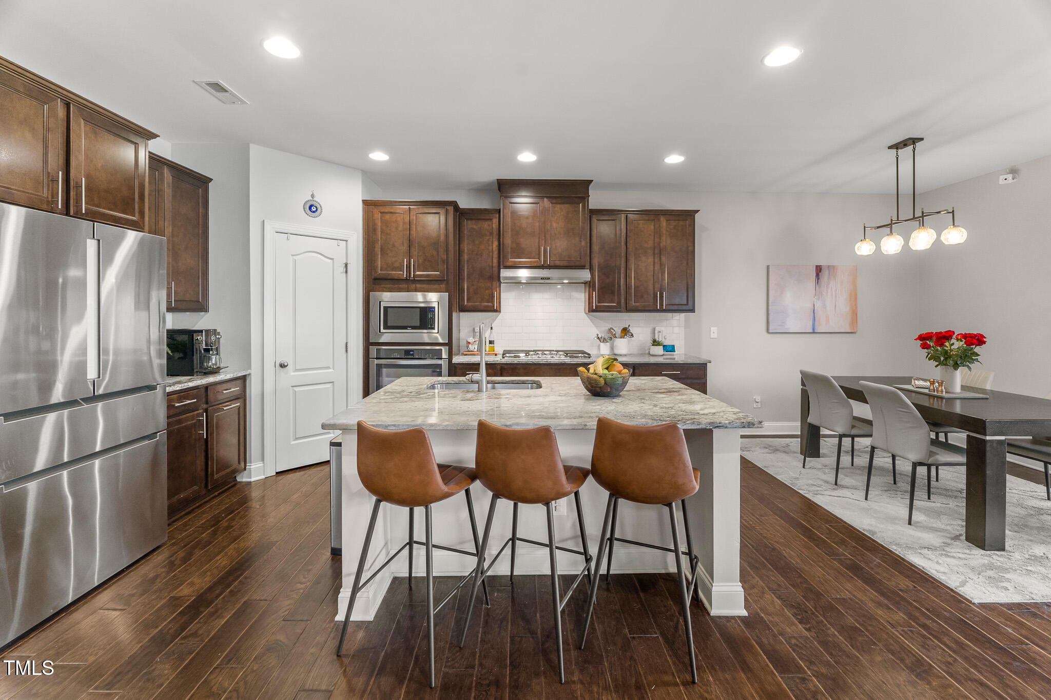 1715 Capstone Drive Durham, NC 27713 - Photo 3 of 53 a kitchen with stainless steel appliances kitchen island granite countertop a stove a refrigerator a kitchen island a dining table and chairs with wooden floor