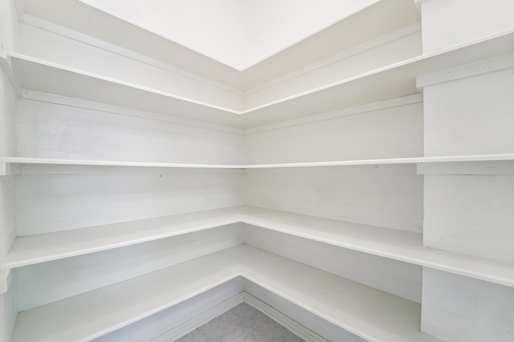 14420 Walters Road, Unit 55 Houston, TX 77014 - Photo 11 of 35 This is a spacious, white, corner pantry with multiple shelves, perfect for organized storage of kitchen essentials.