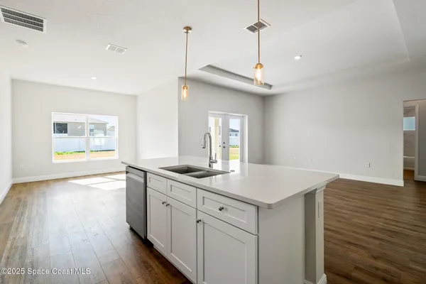 a kitchen with a sink stove and wooden floor