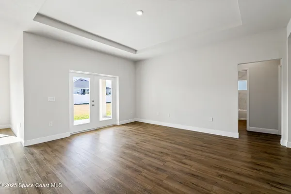 a view of an empty room with wooden floor and windows