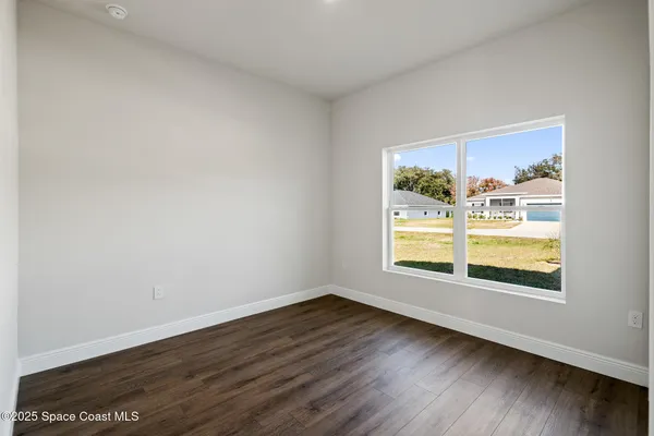 a view of an empty room with wooden floor and closet