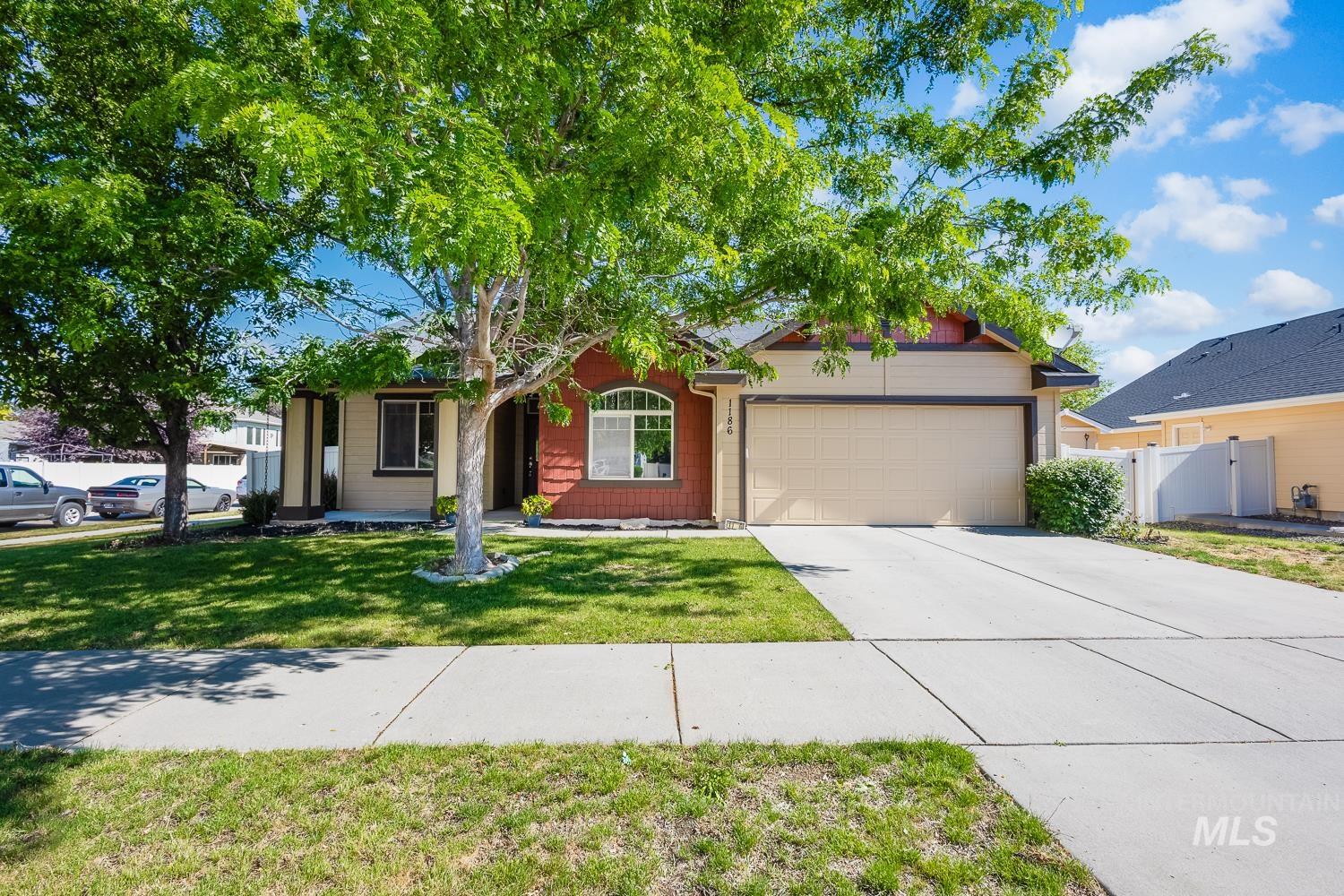 1186 East Observation Street Meridian, ID 83642 - Photo 5 of 33 Single-story home featuring a two-car garage, concrete driveway, and a front lawn with mature trees