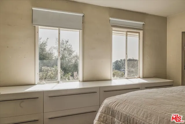 a bedroom with a bed and a large window with outer view