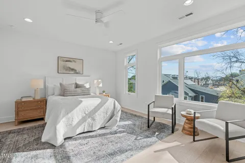 a bedroom with a bed a chair and next to a window