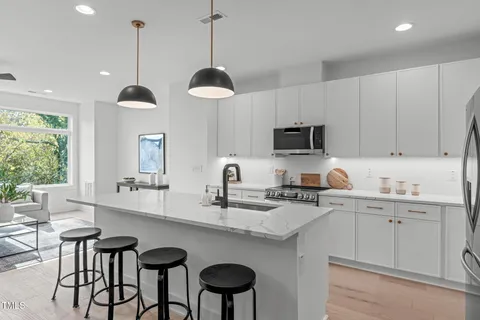 a kitchen with stainless steel appliances granite countertop a sink a stove a dining table and chairs