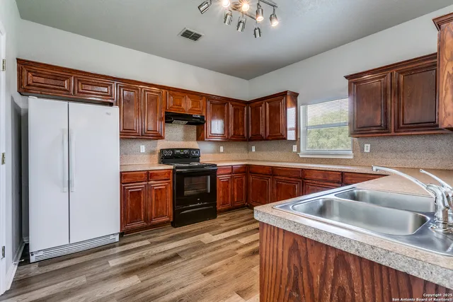 a kitchen with stainless steel appliances granite countertop a sink dishwasher stove and refrigerator with wooden floor