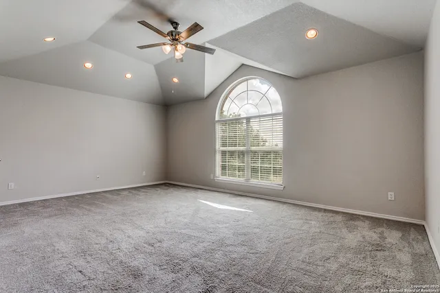 an empty room with windows and ceiling fan