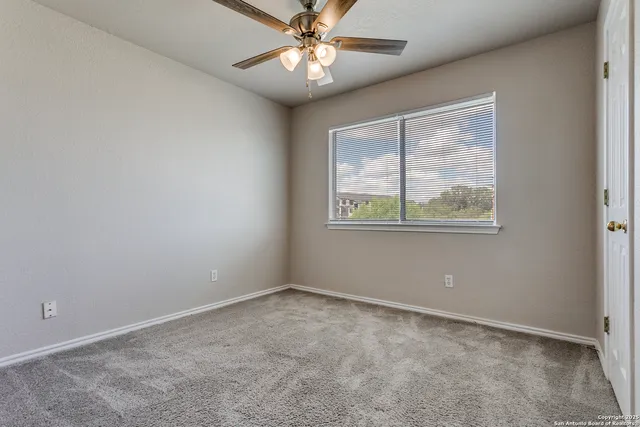 an empty room with a window and a fan