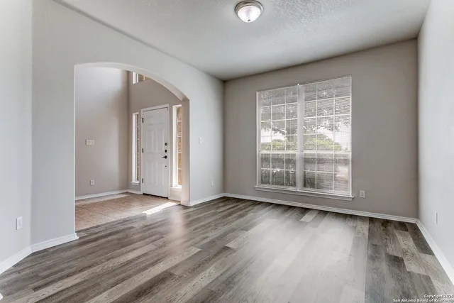 an empty room with wooden floor and windows