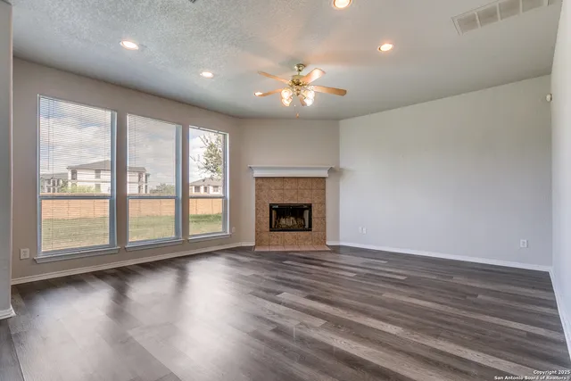 a view of an empty room with wooden floor and a fireplace