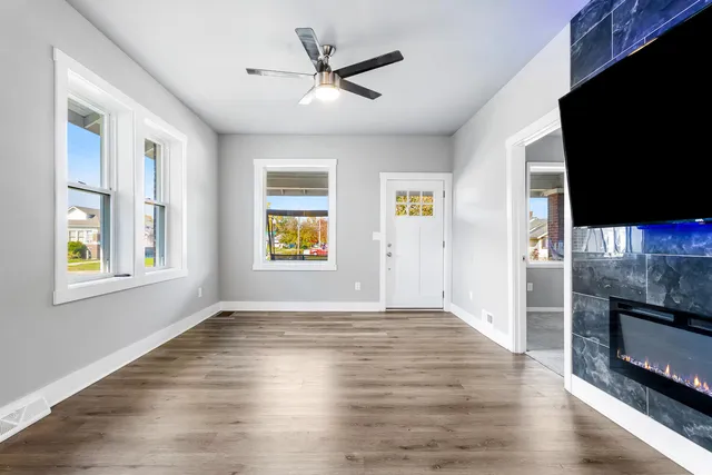 an empty room with windows fireplace and wooden floor