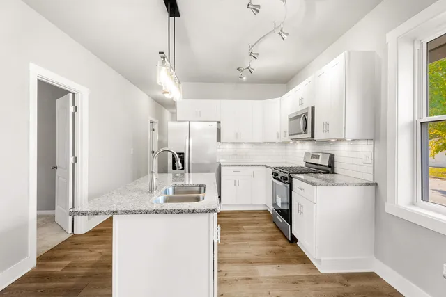 a large kitchen with kitchen island granite countertop a large center island a sink stainless steel appliances and window