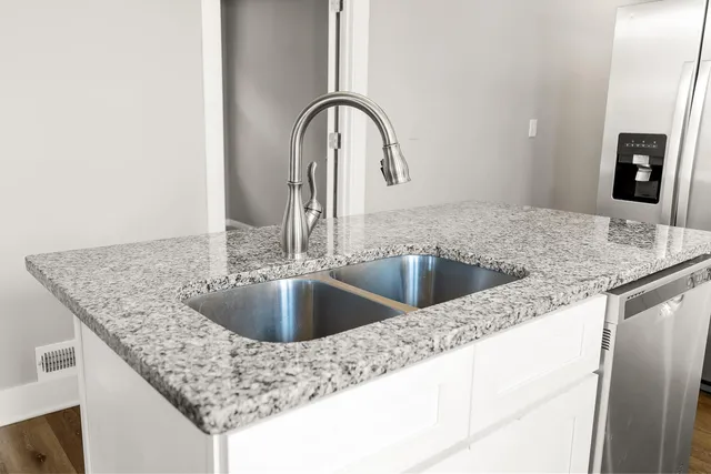 a kitchen with granite countertop a sink and a wooden floor