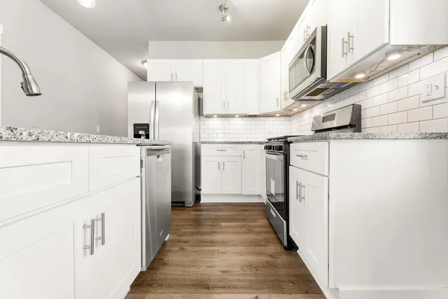 a kitchen with white cabinets and refrigerator