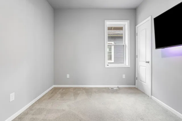 an empty room with windows and fireplace
