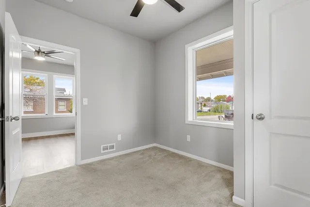 an empty room that has a window and a ceiling fan