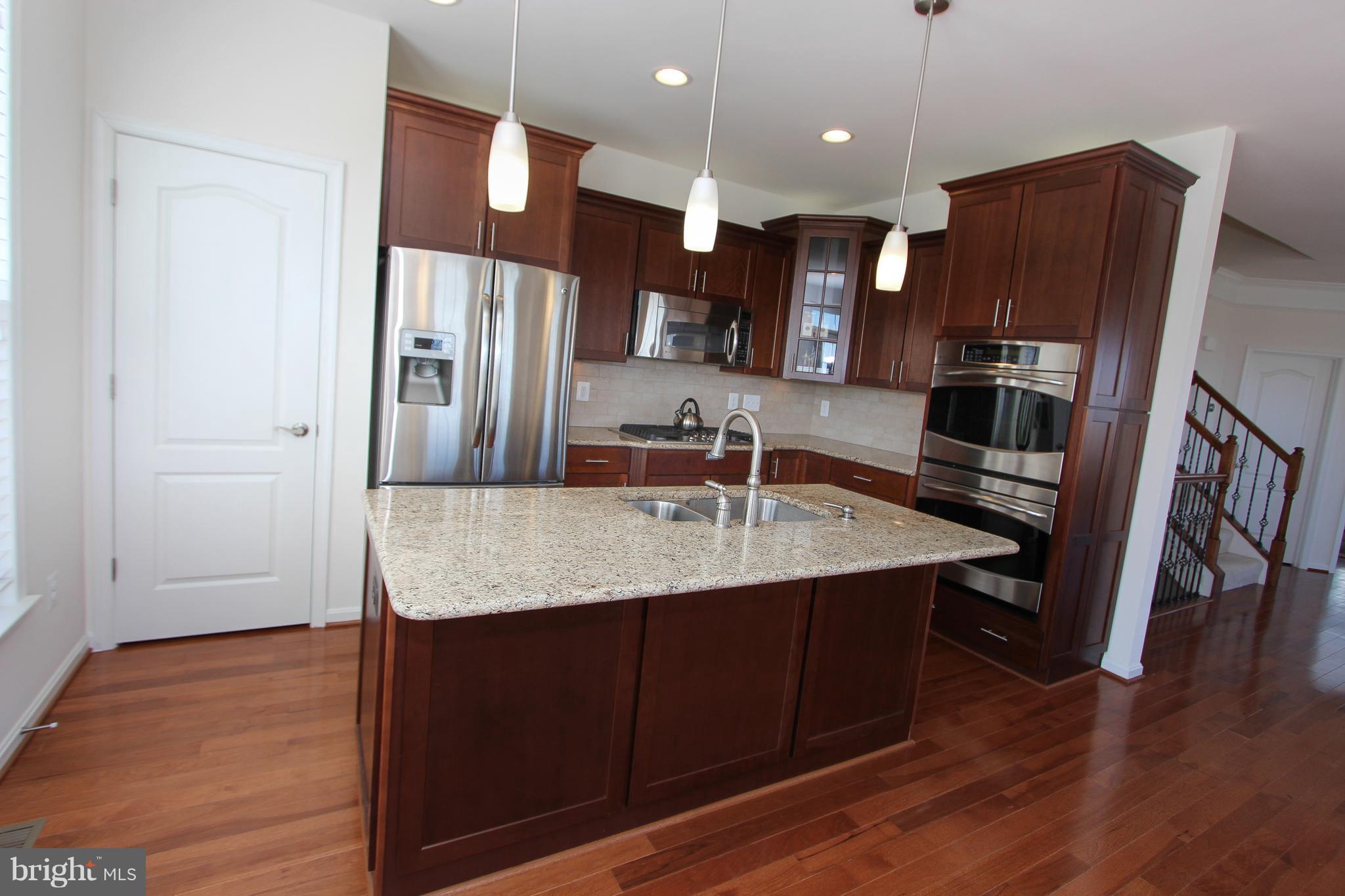 22629 Hawkbill Square Ashburn, VA 20148 - Photo 18 of 30 a kitchen with stainless steel appliances granite countertop a refrigerator a sink and wooden cabinets