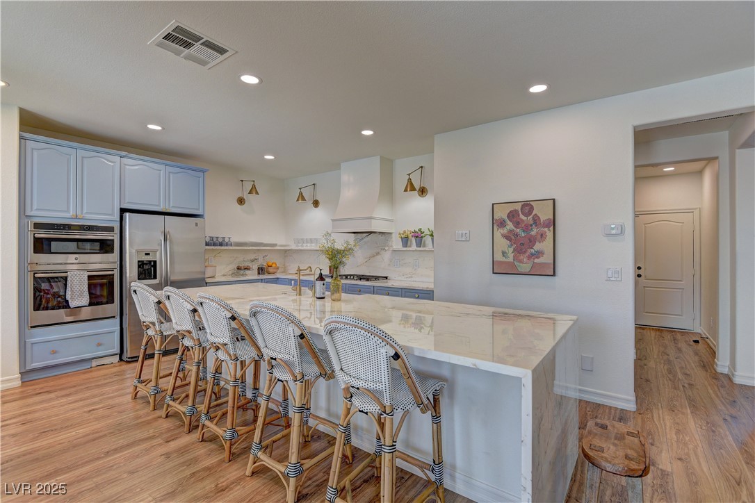 9992 South Sky Parlor Road Las Vegas, NV 89178 - Photo 10 of 42 Kitchen with custom range hood, light wood-type flooring, recessed lighting, visible vents, and stainless steel appliances