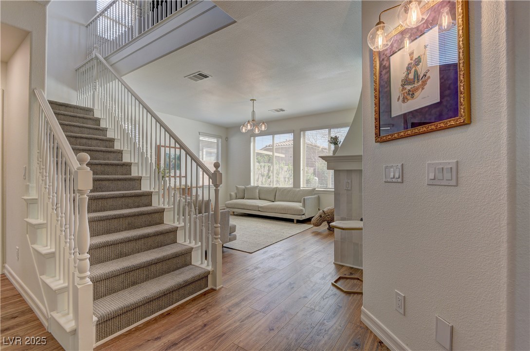 9992 South Sky Parlor Road Las Vegas, NV 89178 - Photo 14 of 42 Stairway with visible vents, wood finished floors, a textured wall, baseboards, and a notable chandelier
