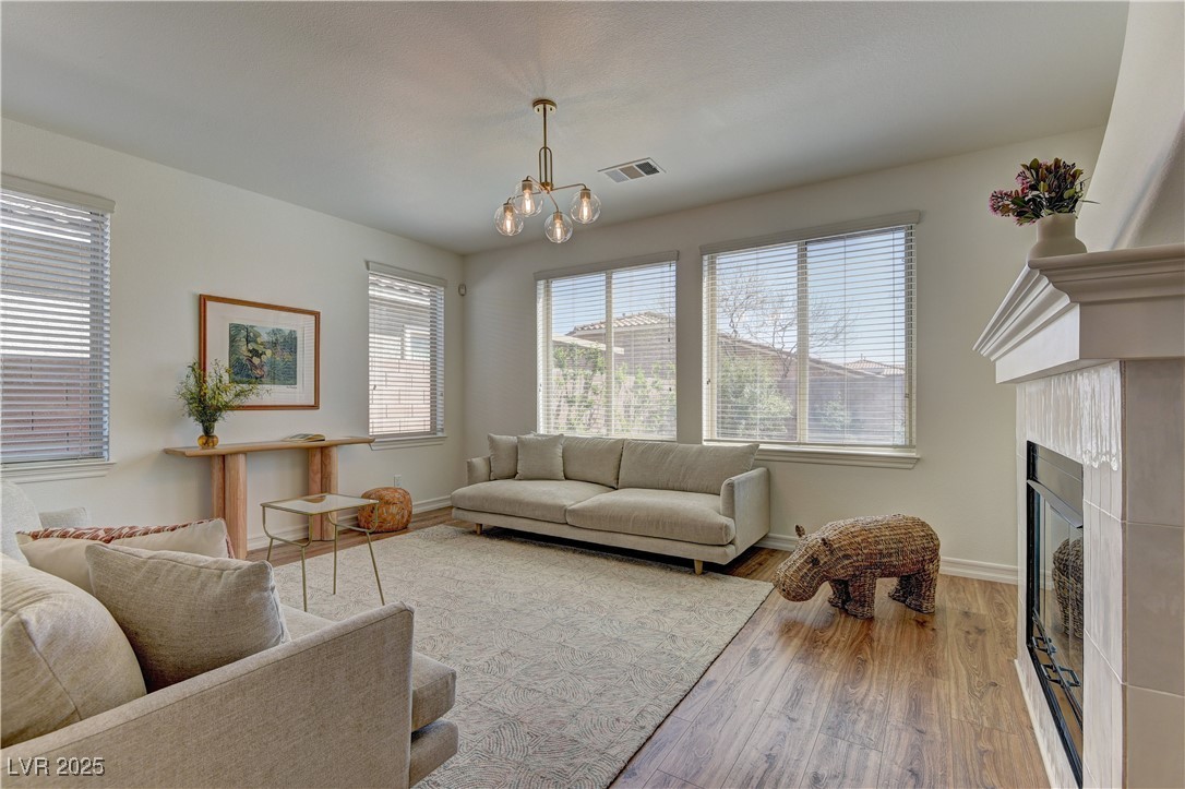 9992 South Sky Parlor Road Las Vegas, NV 89178 - Photo 15 of 42 Living room with visible vents, baseboards, a chandelier, a fireplace, and wood finished floors