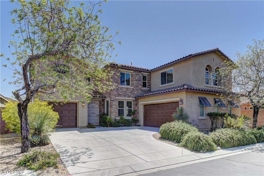 9992 South Sky Parlor Road Las Vegas, NV 89178 - Photo 2 of 42 Mediterranean / spanish home featuring stone siding, a garage, a tile roof, stucco siding, and driveway