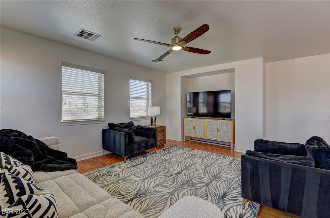 9992 South Sky Parlor Road Las Vegas, NV 89178 - Photo 21 of 42 Living area with visible vents, baseboards, a ceiling fan, and wood finished floors