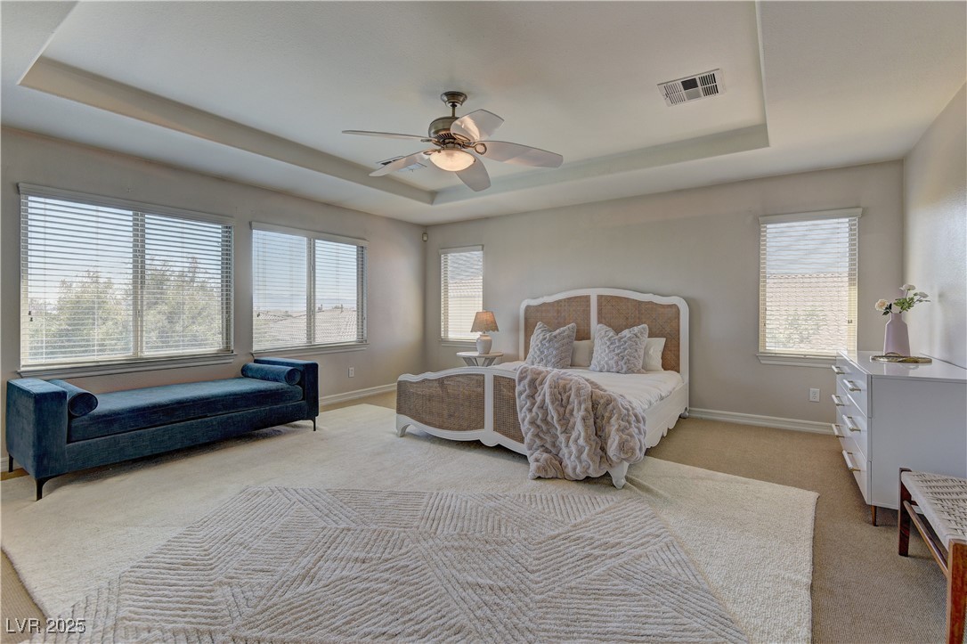 9992 South Sky Parlor Road Las Vegas, NV 89178 - Photo 22 of 42 Bedroom with a ceiling fan, visible vents, light carpet, a raised ceiling, and baseboards