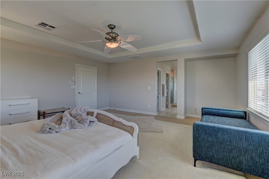 9992 South Sky Parlor Road Las Vegas, NV 89178 - Photo 23 of 42 Bedroom featuring a tray ceiling, light carpet, multiple windows, and visible vents