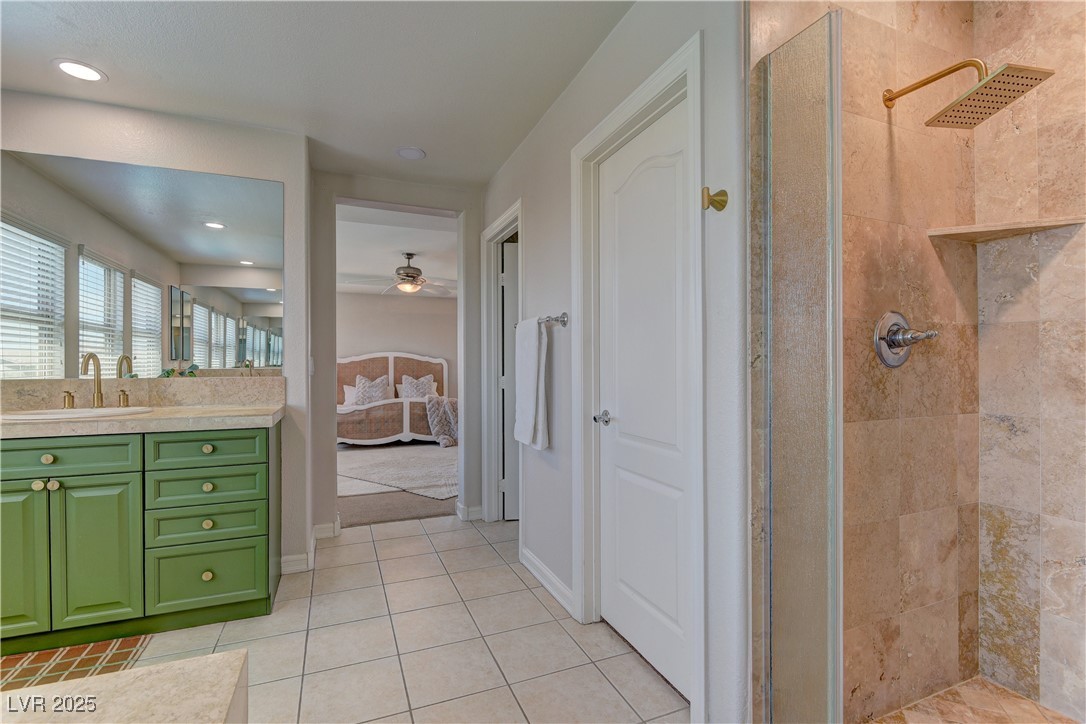 9992 South Sky Parlor Road Las Vegas, NV 89178 - Photo 26 of 42 Ensuite bathroom with ceiling fan, connected bathroom, vanity, tiled shower, and tile patterned flooring